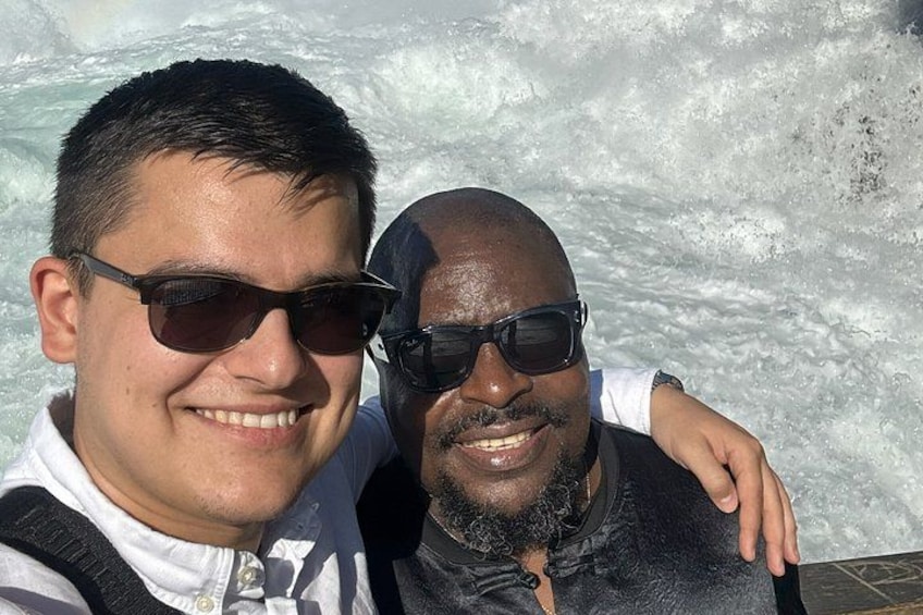 Two people standing in front of a body of water with waves. 3
