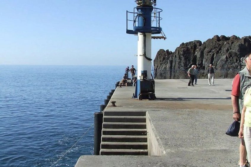 A lighthouse, a pier, and rocky cliffs by the sea. 2