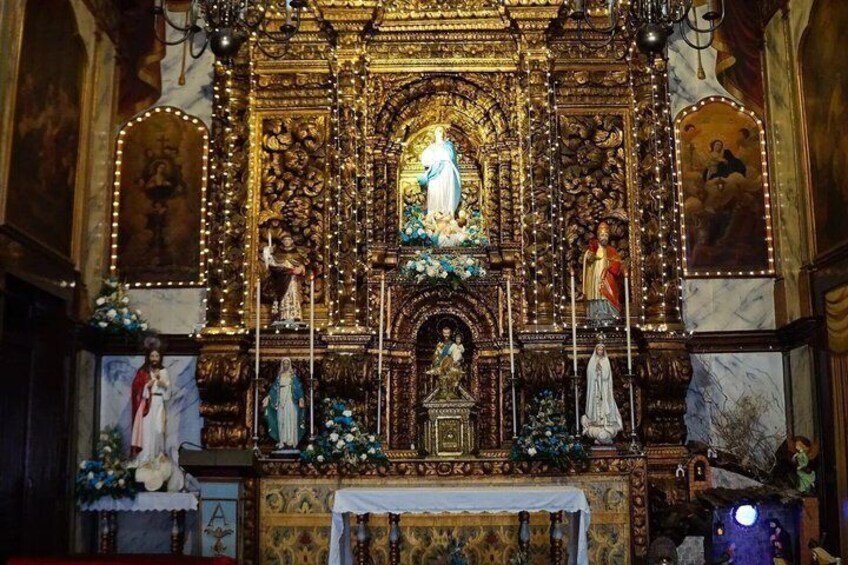 An ornate religious altar with a central statue, surrounded by smaller statues and floral decorations. 3