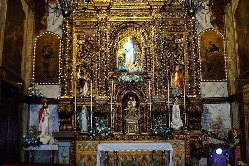 An ornate religious altar with a central statue, surrounded by smaller statues and floral decorations. 3