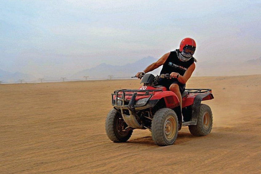 En person kører på en rød quad bike i et ørkenlandskab. 1