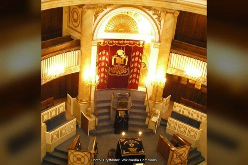 An ornate hall with a central stage, rows of seating, and decorative columns. 4