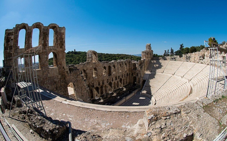 Ancient ruins with an amphitheater and stone structures. 1