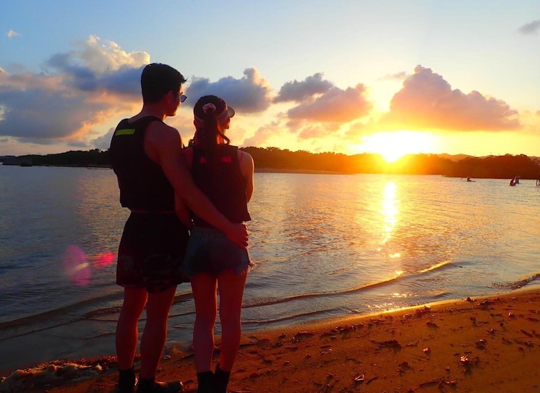 A sunset over a calm body of water with a couple standing on the shore. 5
