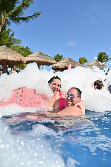 People in a pool with foam and a sign that reads 'SAAVEDOR ARMADA.' 2