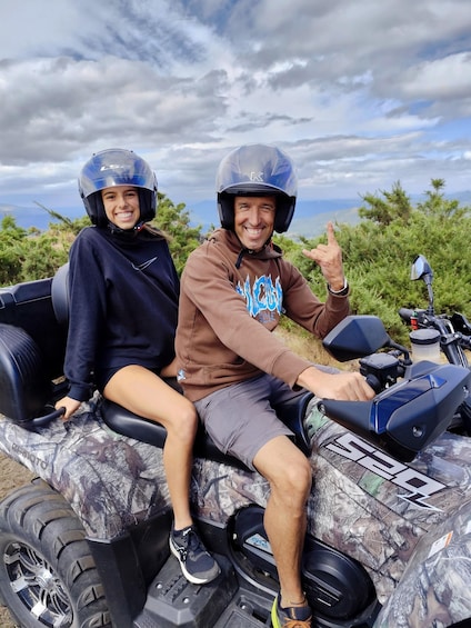 Two people on a quad bike with a mountainous landscape in the background. 1