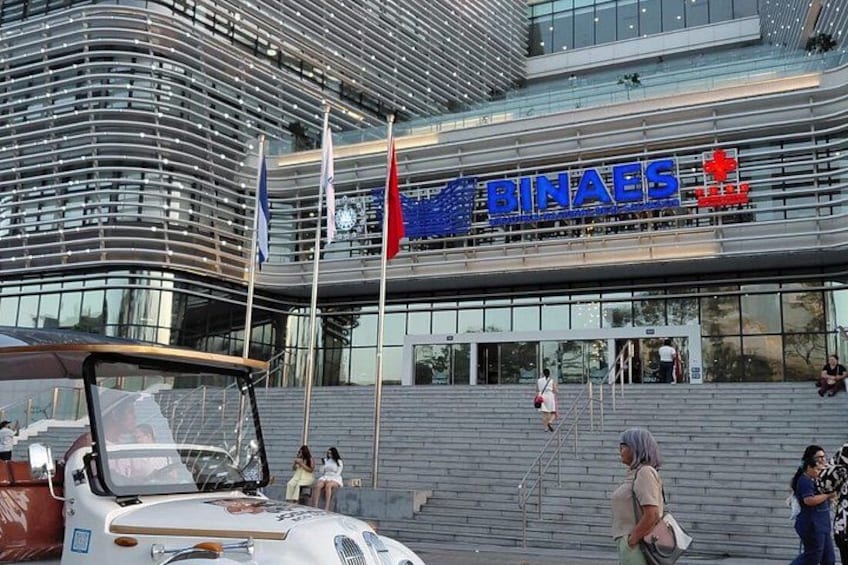 A modern building with the sign 'BINAES' and flags. 2