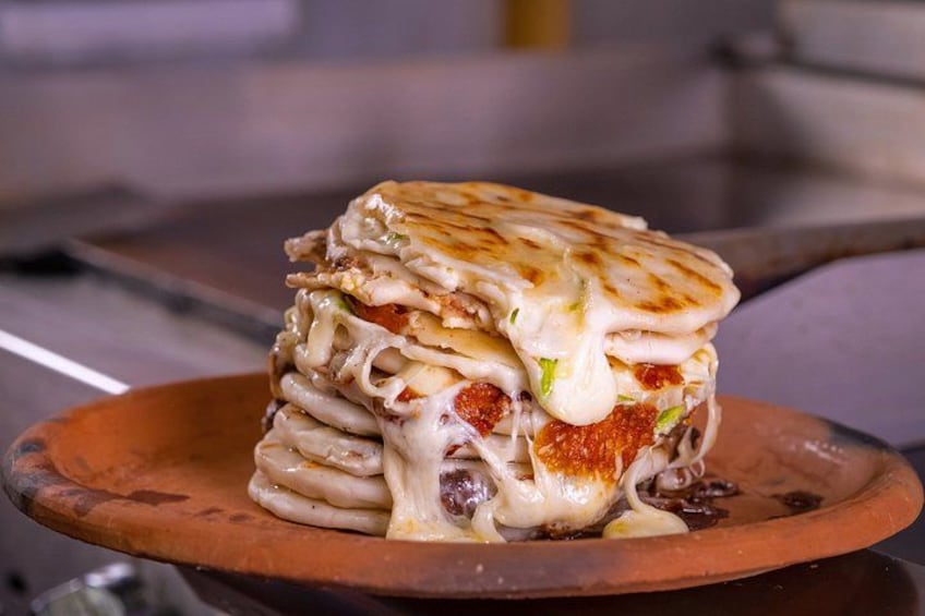 A stack of lasagna with melted cheese on a wooden plate. 1