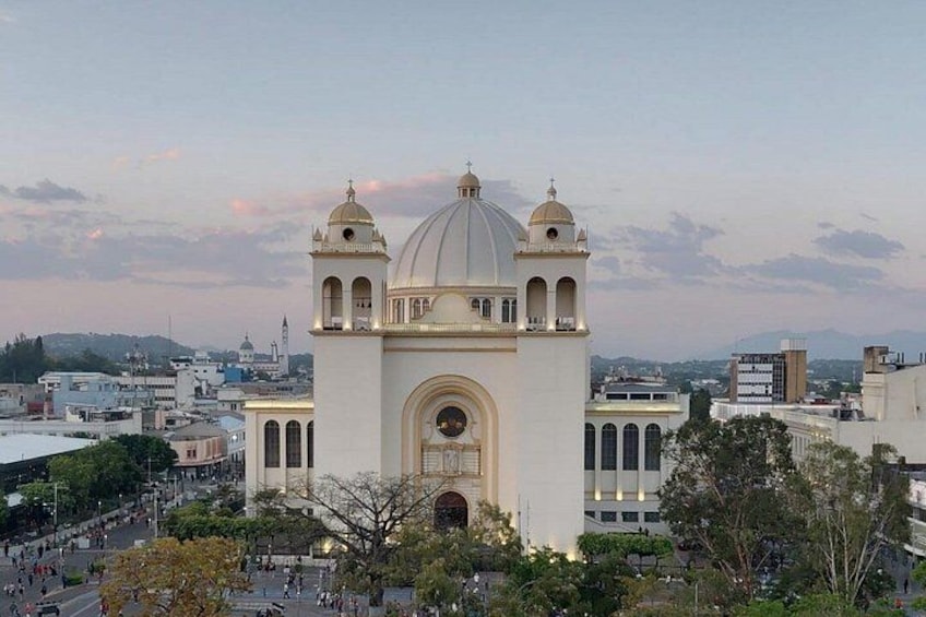 A large white church with a dome and two bell towers, surrounded by urban buildings and trees. 4