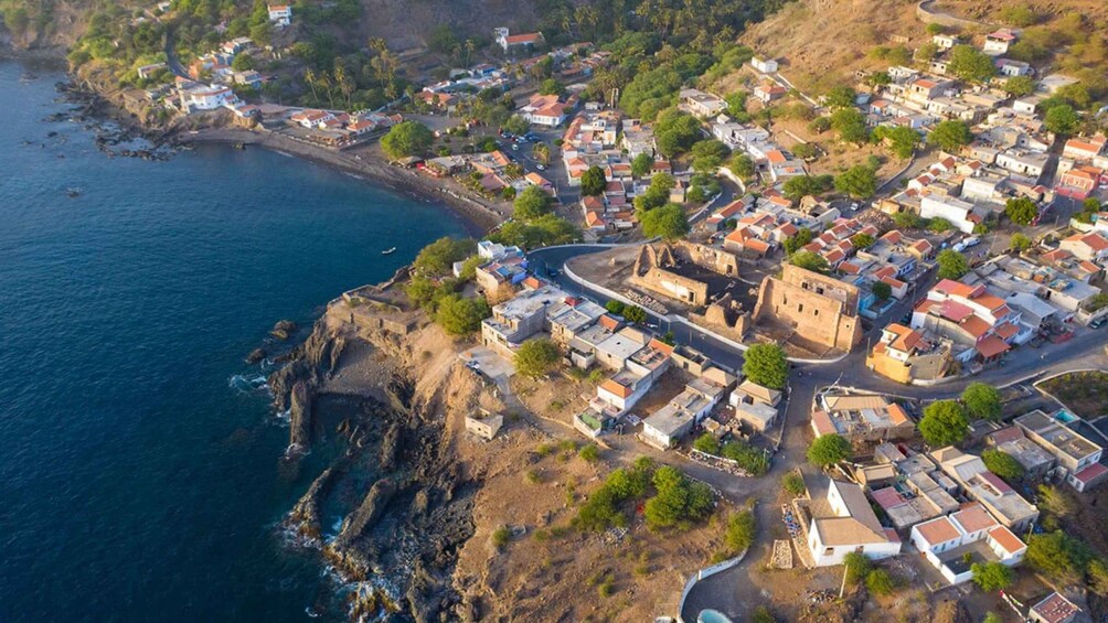 A coastal town with houses, a church, and a cliff overlooking the sea. 1