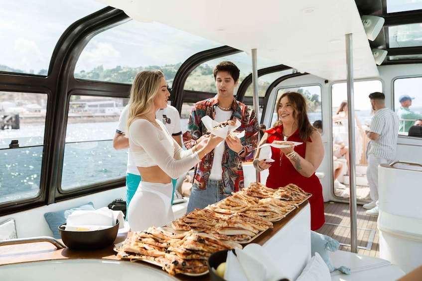 A group of people on a boat with a buffet of pizzas. 5