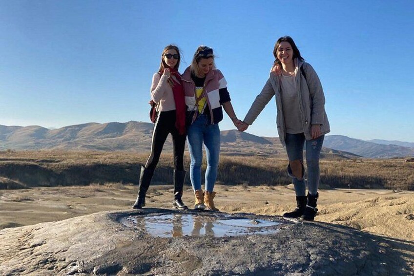 Trois personnes se tenant la main sur un terrain rocheux, avec un paysage montagneux en arrière-plan. 1