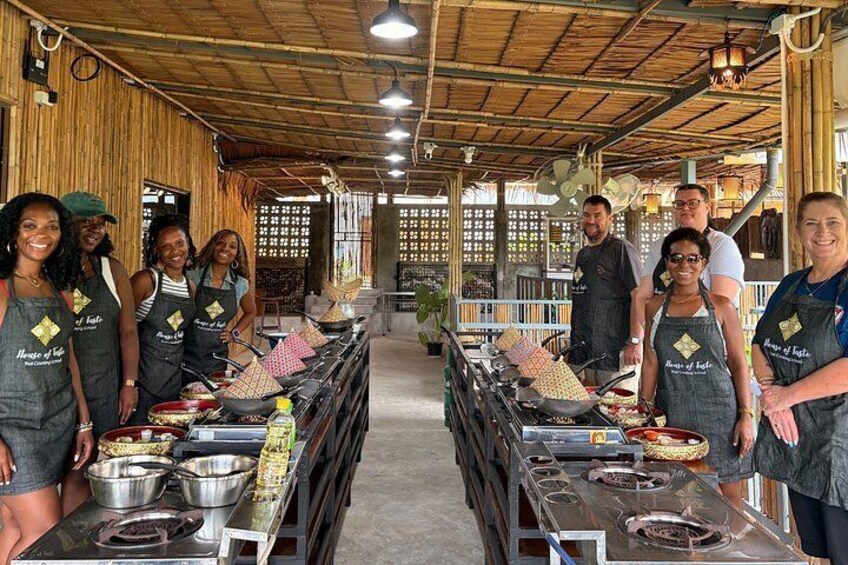 A group of people in aprons standing at a buffet table with various dishes and cooking equipment. 4