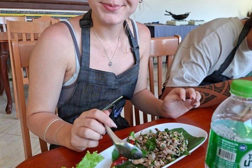 A person sitting at a table with a plate of food and a bottle of sauce. 2