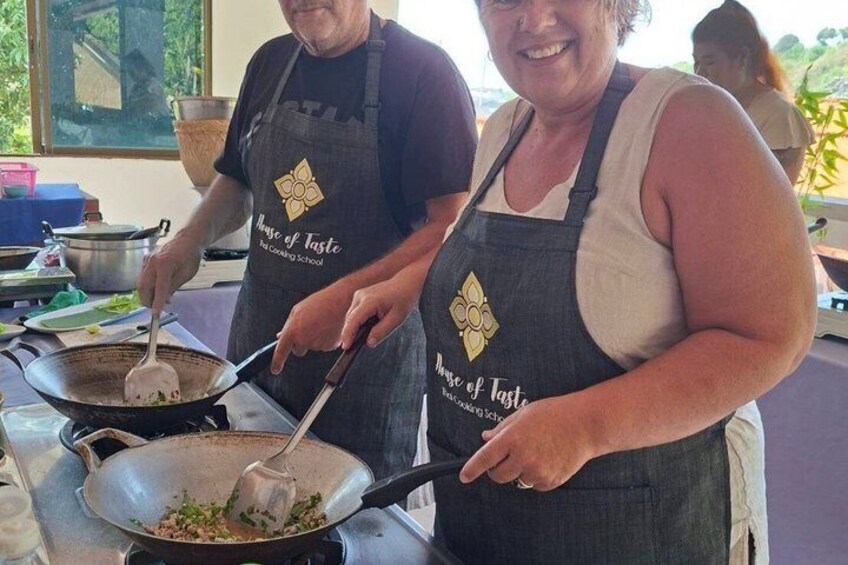 Two people cooking in a kitchen, wearing aprons with 'House of Taste' text. 3