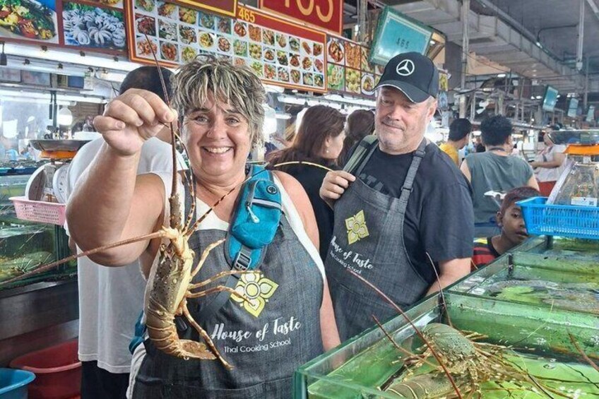 A person holding a large lobster at a seafood market. 1