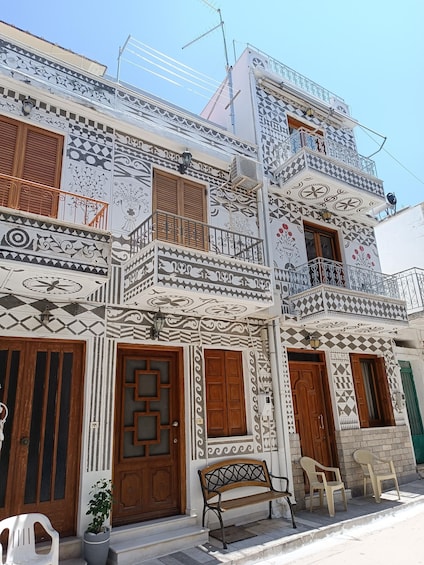 A building with intricate geometric and floral tile patterns, wooden shutters, and a bench outside. 3