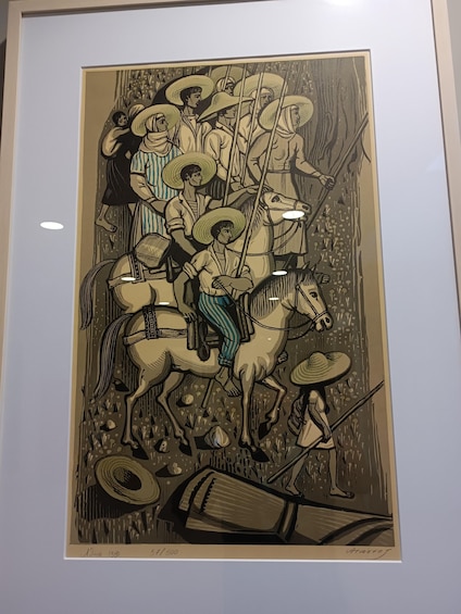 A framed artwork depicting a group of people on horseback, some wearing hats, and one person playing a stringed instrument. 2