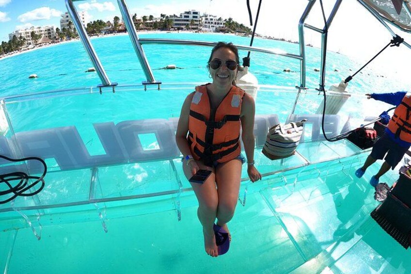 Una persona con chaleco salvavidas en un bote, con agua turquesa cristalina y una playa al fondo. 2