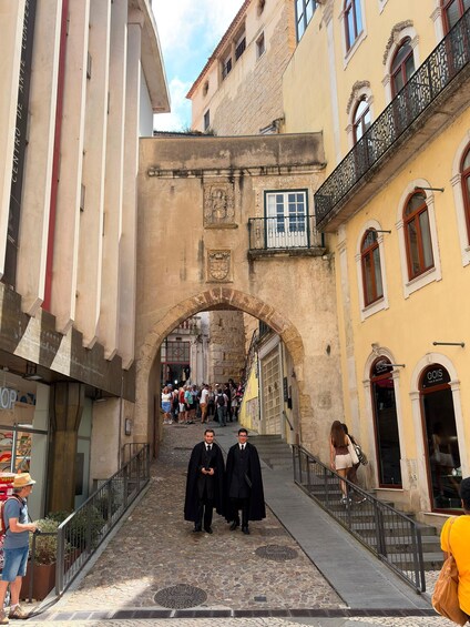 A cobblestone street with an archway, shops, and pedestrians. 4