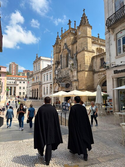 A historic building with ornate architecture, a cobblestone street, and outdoor seating at a café. 5