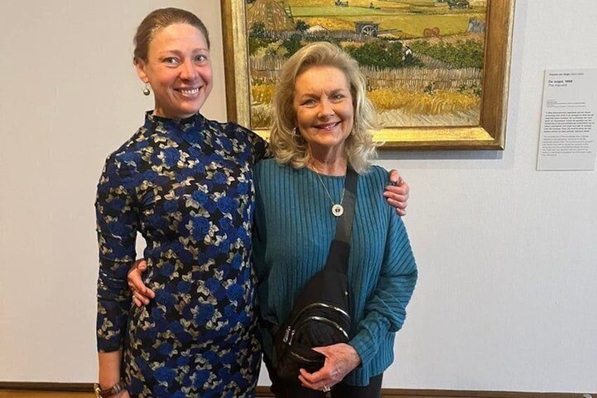 Two people standing in front of a framed painting. 1