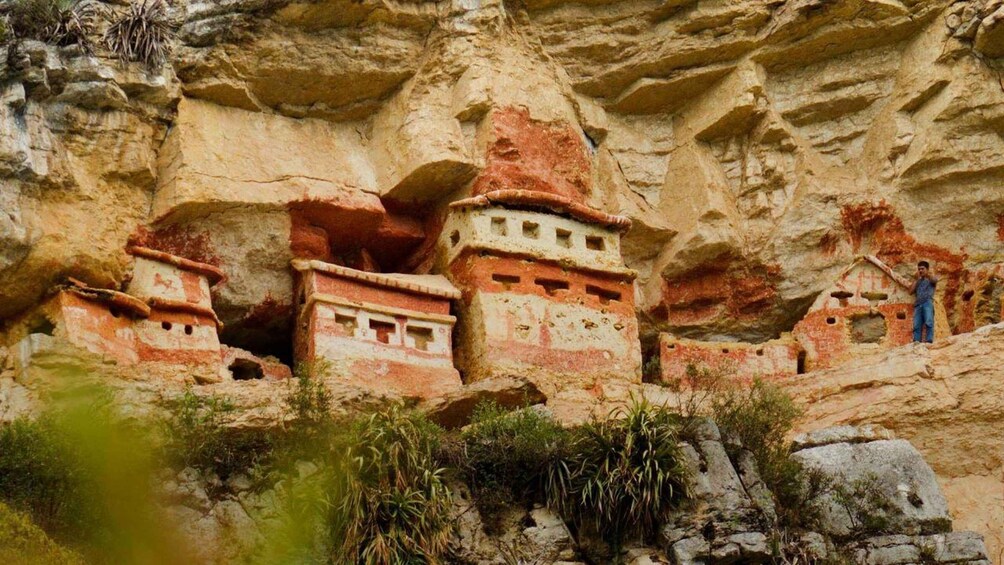 Ancient cliff dwellings with a person standing on a ledge. 4