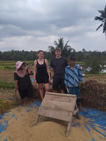 Four people standing in a field with a wooden structure in the foreground. 2