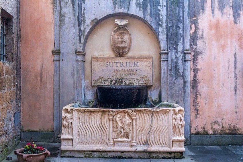 Ein verwittertes Steinmonument mit einer Tafel, auf der 'SUTHIUM' steht, und einem Reliefbild. 5