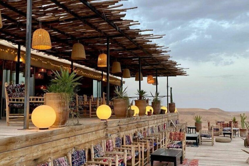 A wooden deck with hanging lights and potted plants, overlooking a desert landscape. 5