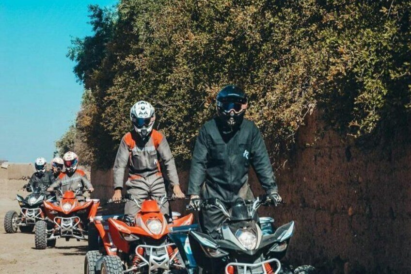 A group of off-road motorcycle riders on a dirt path with a rocky hillside in the background. 1