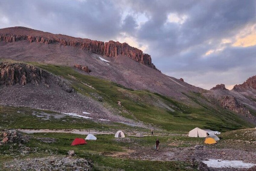 A mountainous landscape with tents and a person walking. 4