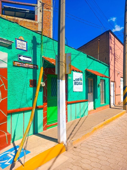 A colorful street with a green building, a sign for 'Viver lechuga,' and a yellow pole. 4