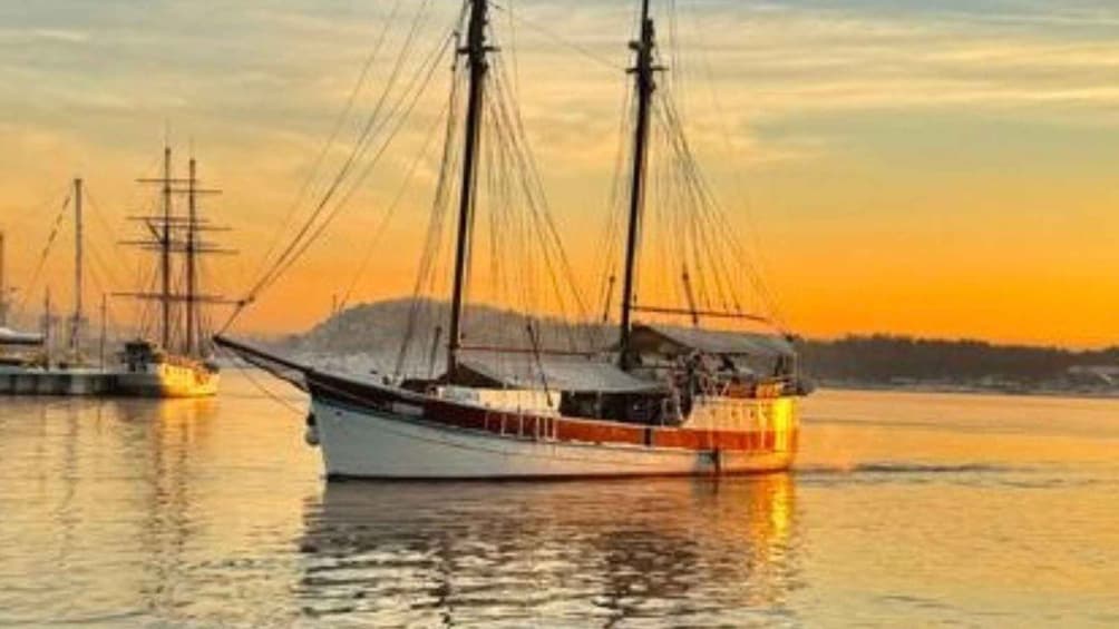 A sailing boat with multiple masts on calm water during sunset. 2