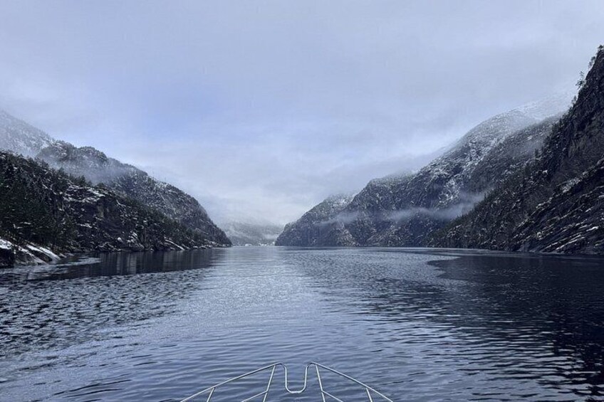A calm river flanked by snow-covered mountains under a cloudy sky. 3