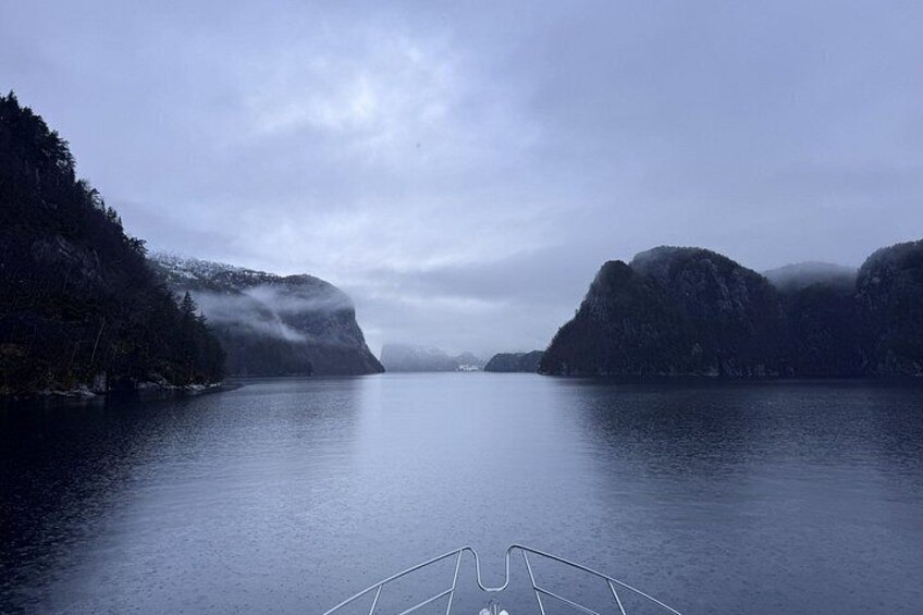 A calm lake surrounded by forested hills under a cloudy sky. 5