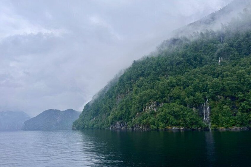 A calm lake with a forested mountain in the background. 5