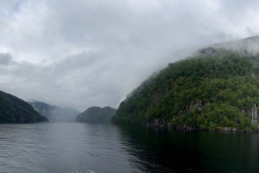 A calm lake surrounded by lush green hills and misty mountains. 3