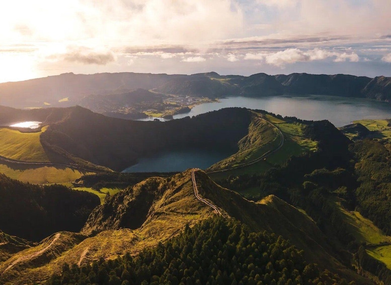 A mountainous landscape with a lake, a winding road, and a distant town. 1