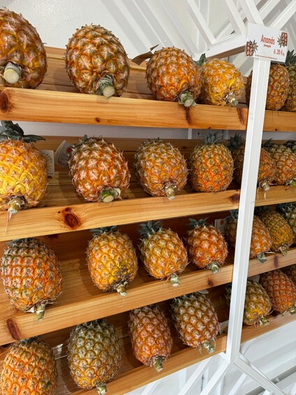 A display of pineapples on wooden shelves in a store. 4