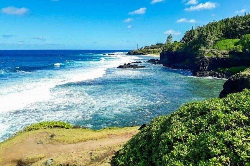 A coastal landscape with waves, greenery, and a clear sky. 3