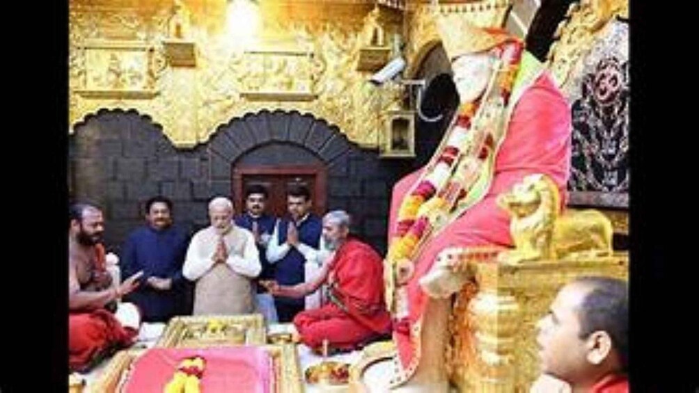 A religious ceremony with participants in traditional attire, a golden statue, and ornate architecture. 1