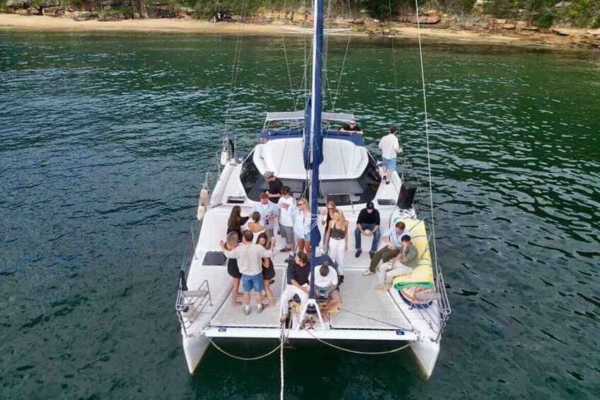 A sailboat with people on deck, surrounded by calm water and a sandy beach in the background. 4