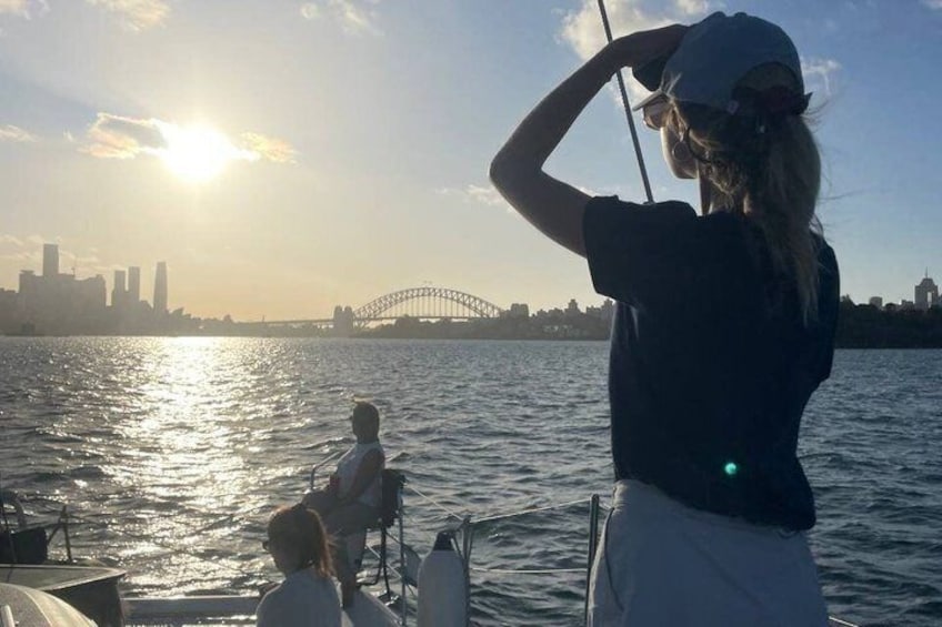 A person fishing on a boat with a city skyline and a bridge in the background. 2