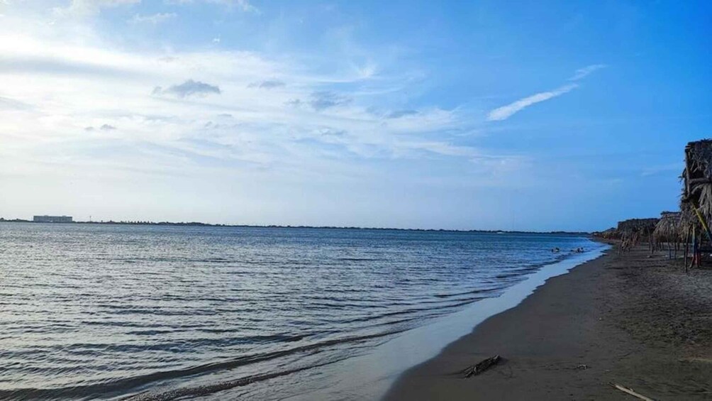 A beach with calm water, a clear sky, and a distant shoreline. 2
