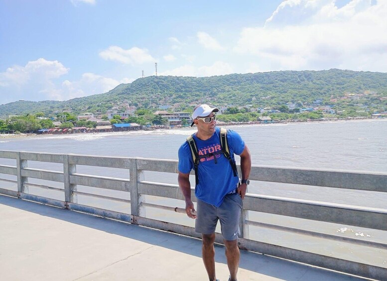 A man standing on a bridge with a coastal landscape in the background. 3