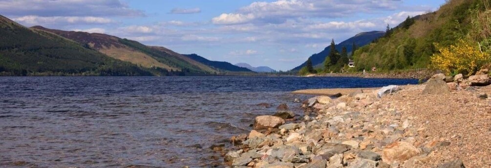 A calm lake surrounded by hills and a rocky shoreline. 4