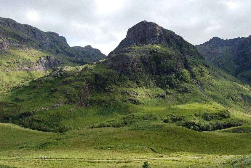 A mountainous landscape with lush green hills and a prominent rocky peak. 1