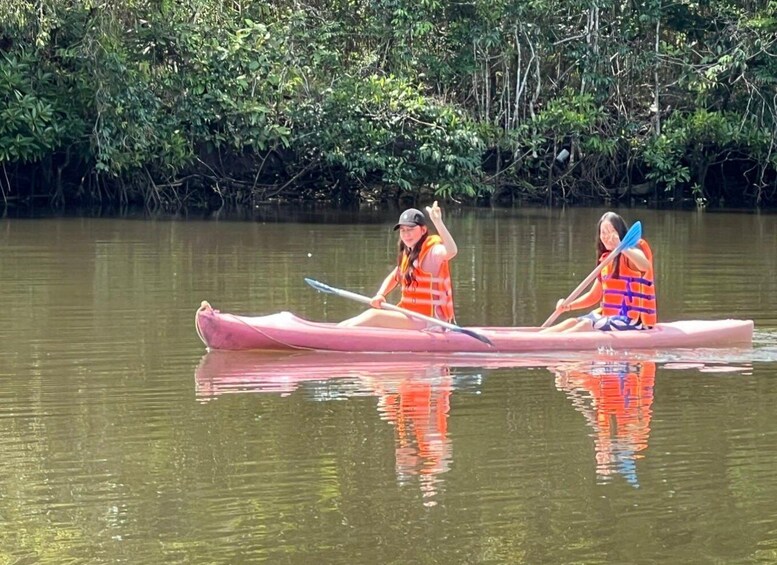 Two people in a canoe on a calm river surrounded by dense greenery. 2