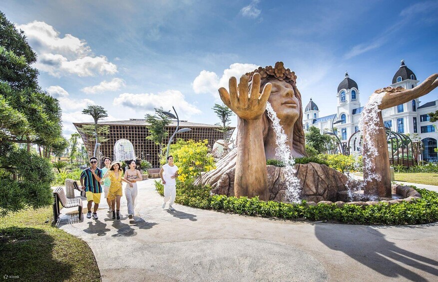 A large sculpture of hands reaching out, a fountain, and a building with domes in the background. 5